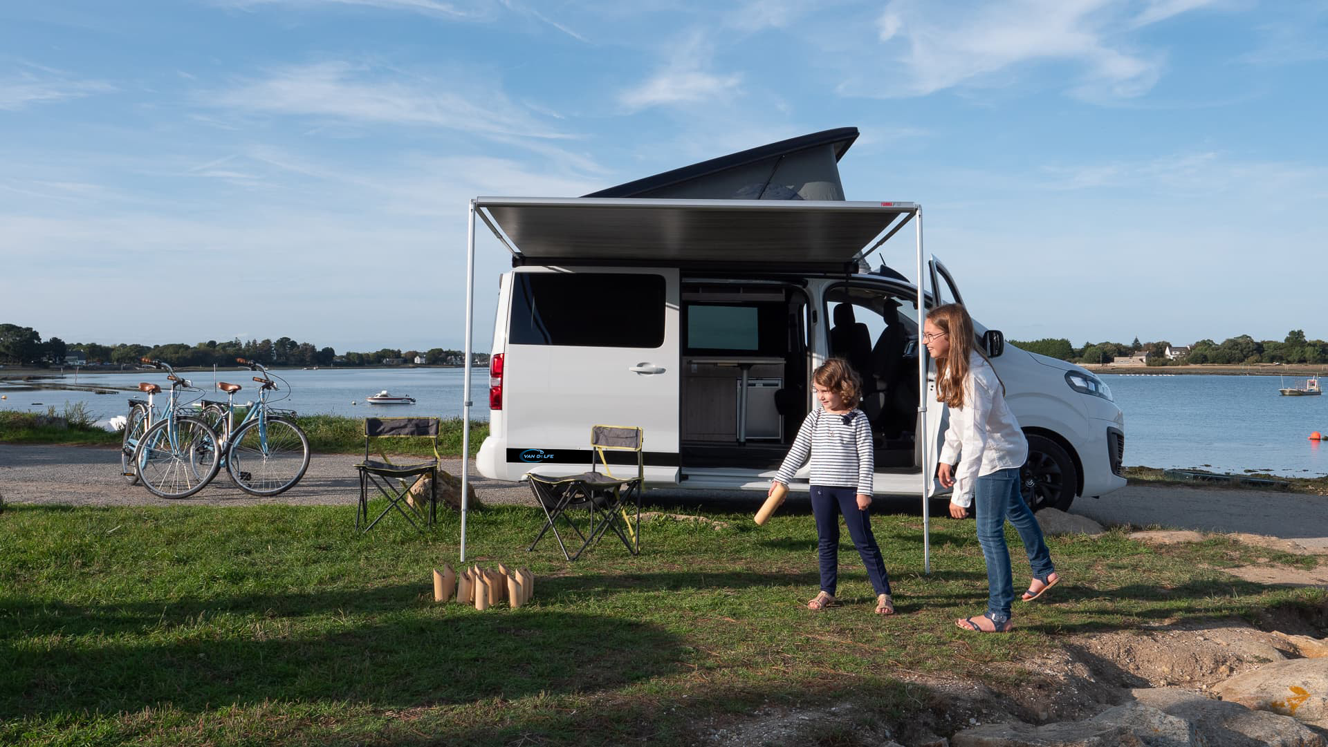 Photo Van Jumpy Blanc aménagé, avec vue sur mer et deux enfants jouant devant.