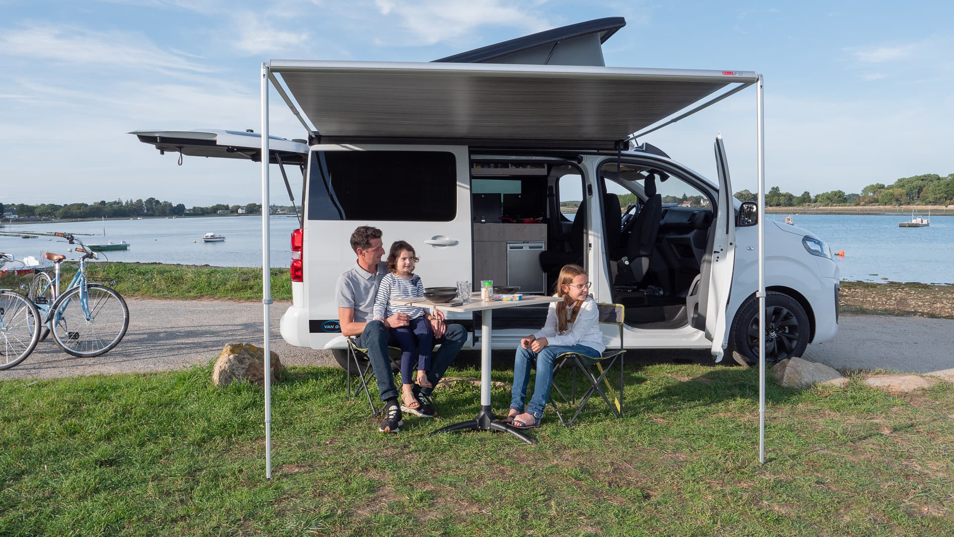 Photo d'une famille relaxant près de leur van aménagé Van Golfe