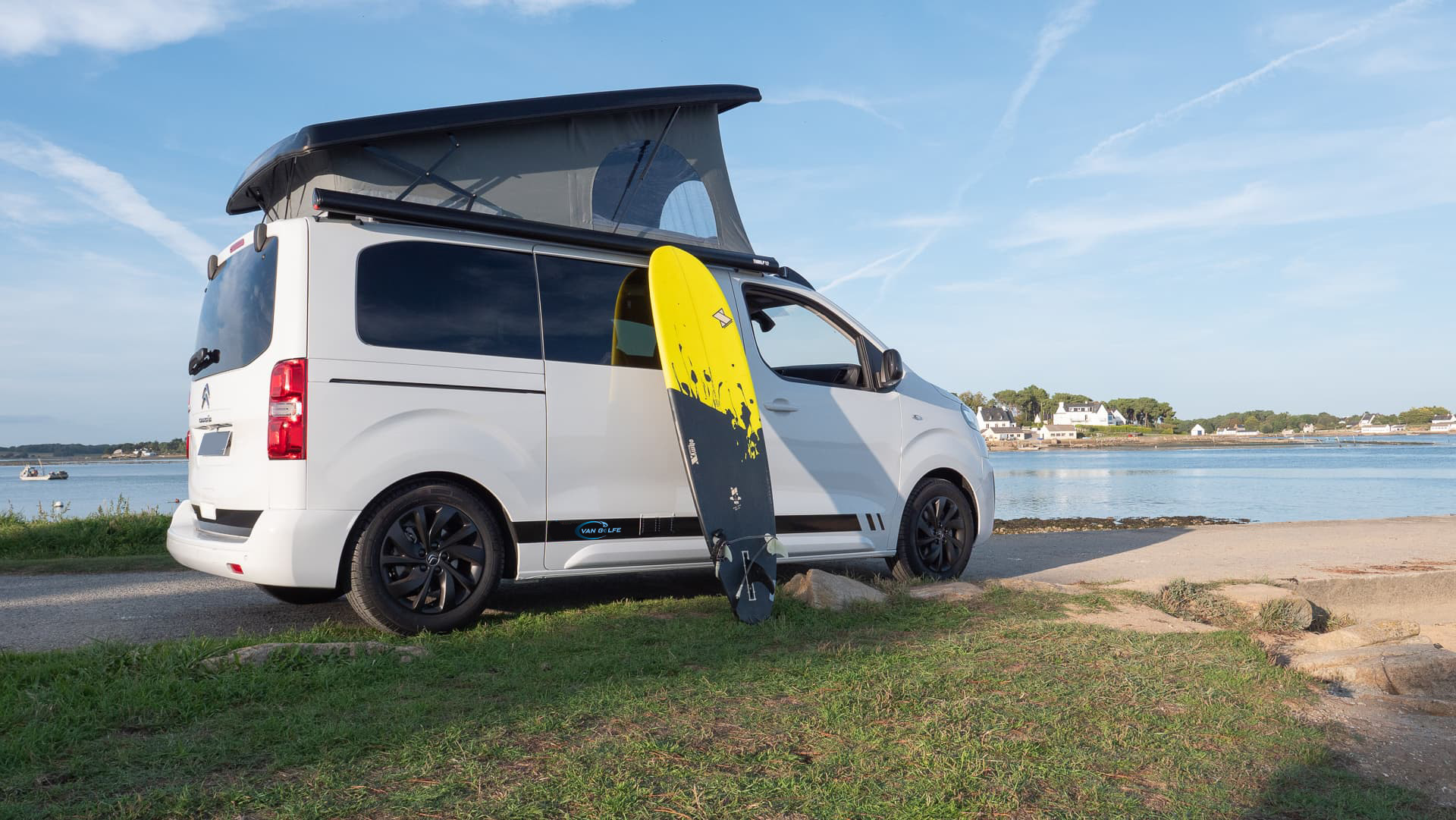 Van aménagé Van Golfe en bord de mer avec une planche de surf sur le côté