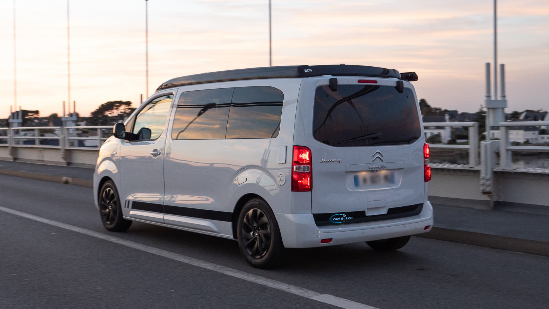 Van aménagé Van Golfe sur la route avec un couché de soleil au loin